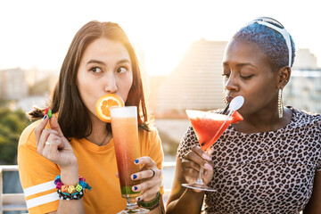 Multiethnic couple of cool lesbian women drinking cocktails