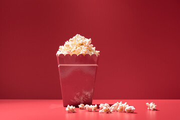 Caja llena de palomitas de maíz sobre fondo rojo. Concepto cine