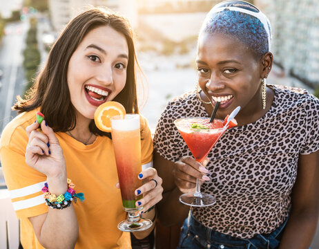 Multiethnic couple of cool lesbian women drinking cocktails