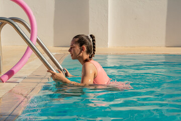 A girl in a swimsuit comes out of the pool