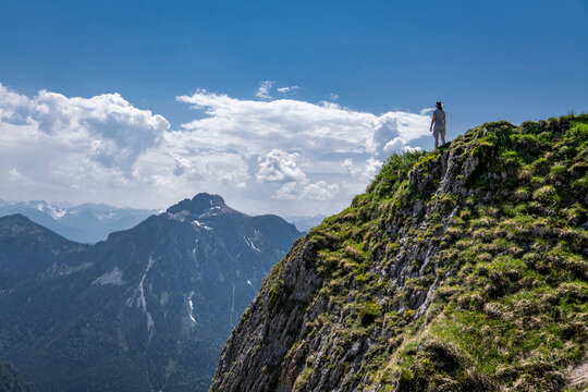Woman standing on mountain looking at another mountain, Tegelberg, Germany
