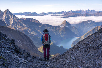 Woman looking into valley of mountains, lakes and clouds, Greina, Switzerland