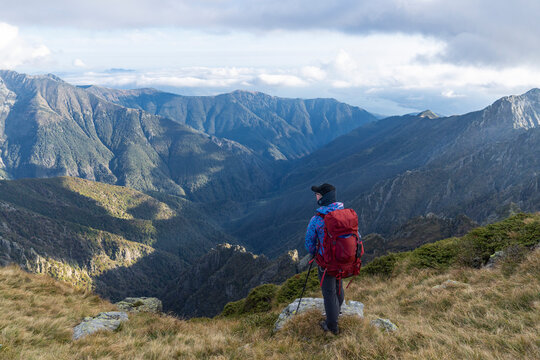 Hiker on ridge looking into vast valley in Val Grande, Italy