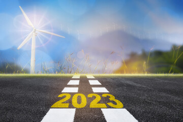 Road to 2023 sustainable lifestyle with wind turbines on mountain background. Renewable clean...