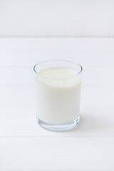 glass of fresh milk on a white wooden table. copy space. vertical frame.