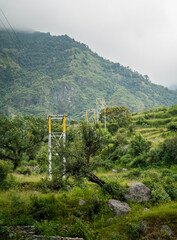 Uttarakhand India. Electricity poles with overhead transformers in remote areas with mountains and forest in the background.