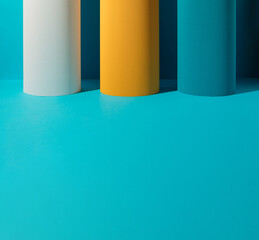 Three paper pillars - white, yellow and blue on blue background with copy space. Geometric...