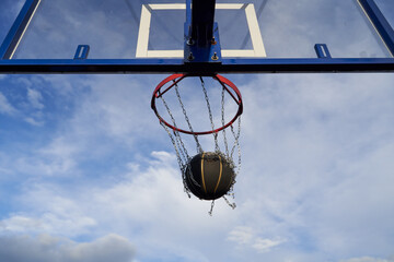 Street basketball ball falling into the hoop. Close up of black ball in the hoop net.
