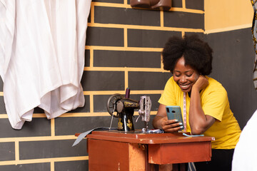 female african tailor checking her phone