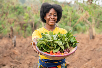 smiling african farmer carrying a basket of vegetables