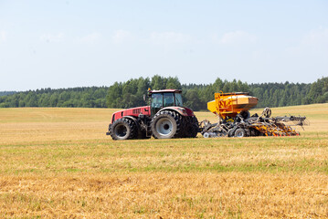 Fototapeta premium Tractor harvests grain in the field. Selective focus.