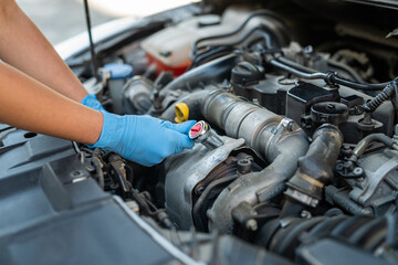 hands of a female mechanic working under the hood of a car in a car service.