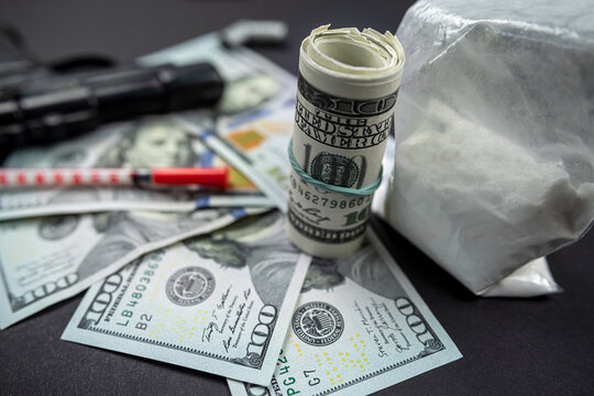 drug heroin lies next to syringes, money dollars weapons isolated on a dark background.