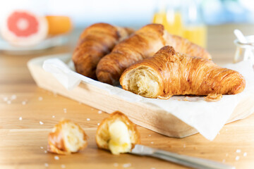 Frische, leckere Croissants mit gesalzener Butter und Saft, vor Fenster