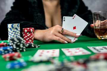 young woman is holding gambling chips and casino cards at the table in a beautiful dress.