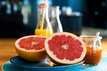 Grapefruit aufgeschnitten auf blauem Teller. und Saft vor dunklem Hintergrund 
