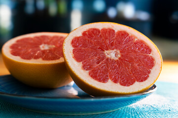 Grapefruit aufgeschnitten auf blauem Teller. Dunkler Hintergrund 