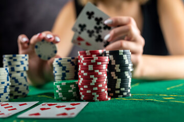 Fototapeta na wymiar Female hand taking poker chips from pile at round poker table.
