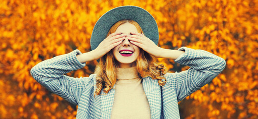 Autumn portrait of cheerful happy laughing woman covering her face with her hands wearing round hat...