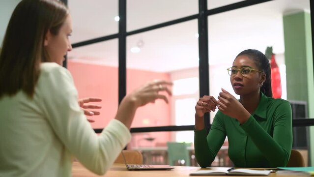 Work team brainstorming sitting in the modern boardroom, coworkers discussing business tasks during morning meeting, concentrated african-american female employee listening while colleague talking