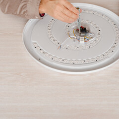 close-up of male hands using an indicator screwdriver in maintenance of an LED lamp
