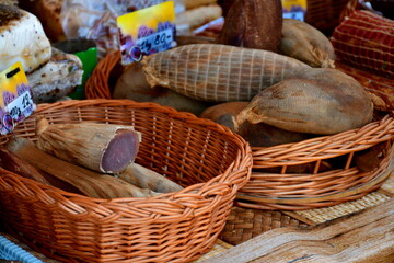 A close up on baskets of medieval style meats and handmade sausages sold during a medieval fair in Poland arranged from smoked to raw seen on a sunny summer day on one of the stalls