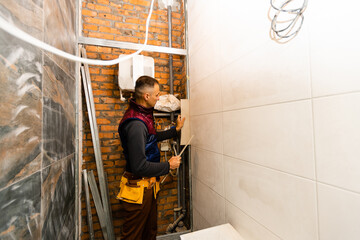 Naklejka na ściany i meble Laying Ceramic Tiles. Tiler placing ceramic wall tile in position over adhesive