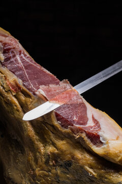 Faceless chef cutting delicious ham leg with knife