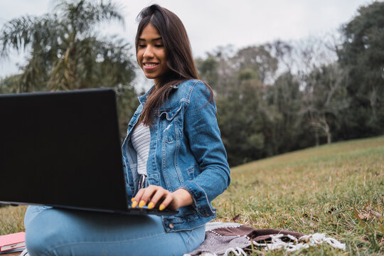 Happy woman using laptop in park
