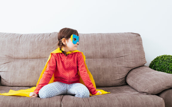 Girl in mask and cape pretending to be superhero