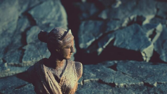 ancient statue of woman on rocky stones