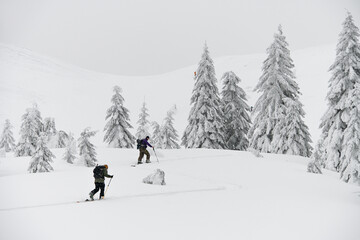 Two guys skiers with hiking equipment walking at snow on mountain slope. Beautiful landscape