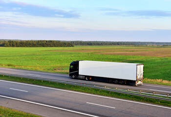 Truck with semi-trailer driving on highway on sunset. Goods delivery by roads. Services and Transport logistics. Lorry Transport in motion. Long Self-driving lorries. Semi-trailer truck on freeway..