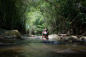 Girl on vacation in a spa. Girl bathing in a river. Woman with hat. River with stones and bamboo