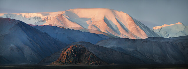 Mountains of Western Mongolia, snow on the peaks, desert mountain slopes, sunrise light