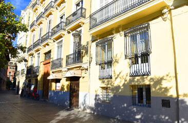 Pavement with a footpath at facade of residential building in city. Building facade with windows and balconies. Lattices on the windows of a residential building. Buildings architecture in Europe.