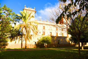 Fototapeta premium Old historical building in the Antique architectural style near the city park. Palm trees in the park against the backdrop of a historic building. Valencia Central Park with gardens and green trees.