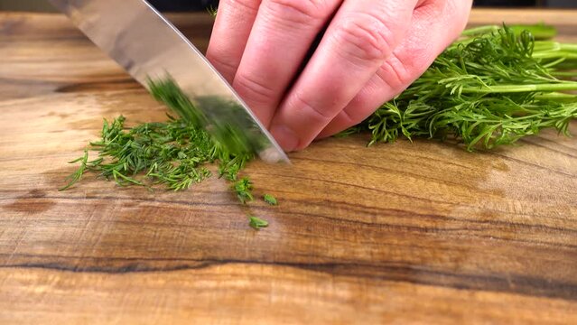 The cook cuts fennel on a wooden cutting board.