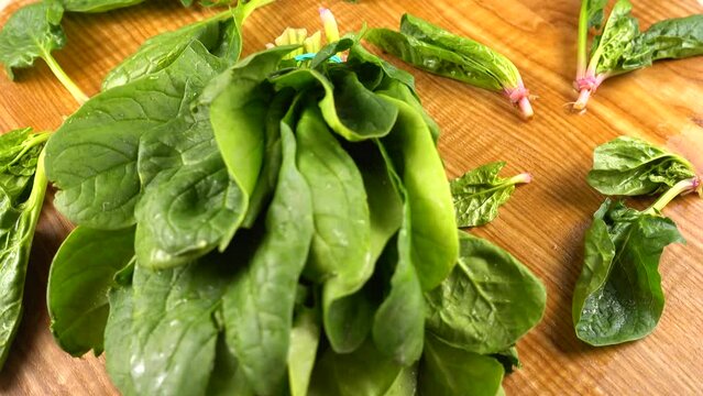 Spinach leaves on a wooden cutting board.