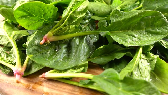 Spinach leaves on a wooden cutting board.
