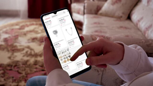 A teenager looks at goods in online store on a smartphone.