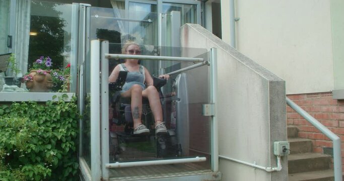 MS Woman in motorized wheelchair in elevator outside house / Sheffield, UK