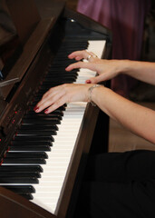 female hands play music on white and black piano keys
