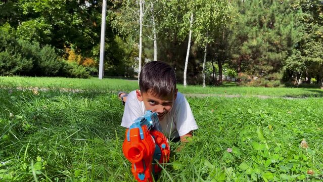 A boy playing with his nerf gun at the park. 