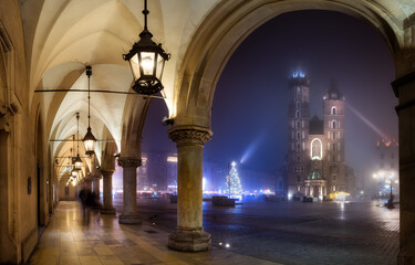 A foggy, autumn night on the main square in Krakow, the St. Mary's Basilica and the cloth hall....