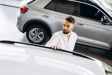 Young man in car showroom choosing a car