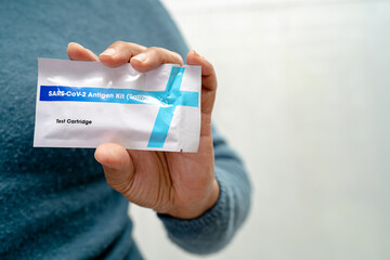Asian doctor in PPE suit show positive test result with Saliva Antigen Test Kit for check Covid19 coronavirus in hospital.