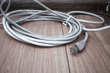 Rolled up ethernet cable on the dirty floor. The disconnected Internet cable lies on the floor