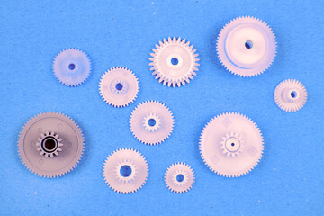white plastic gears on a blue background. connection mechanism details. subject of movement