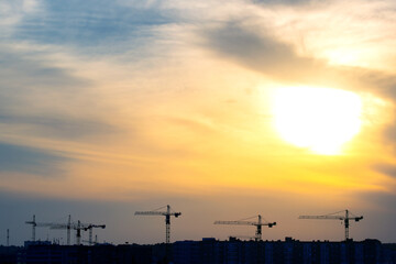 silhouettes of building cranes in the evening sky against the backdrop of sunset. urban building industry